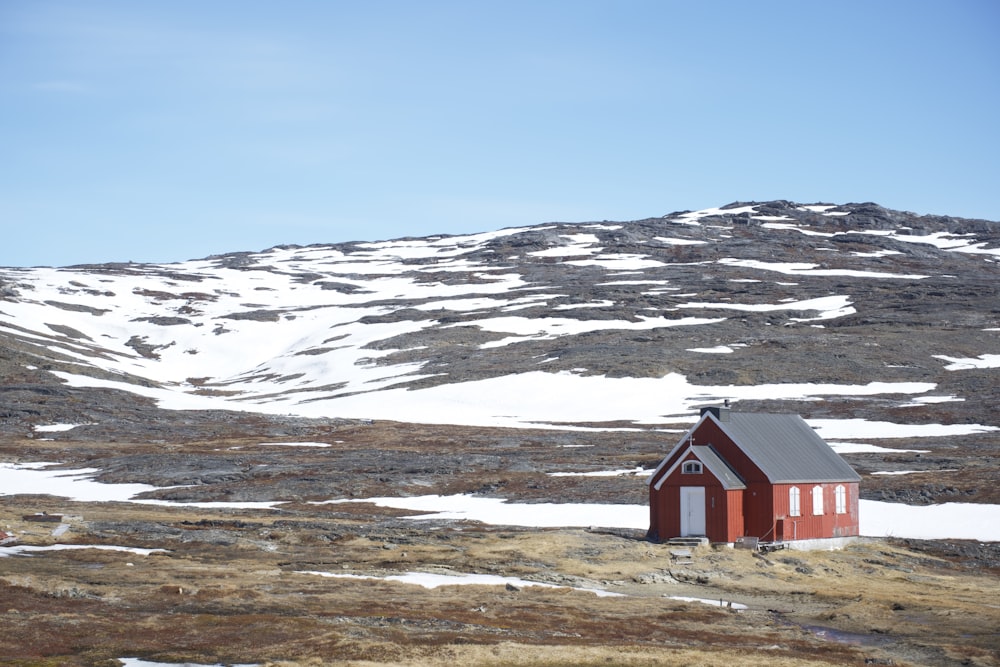 red and white house on brown field near snow covered mountain during daytime