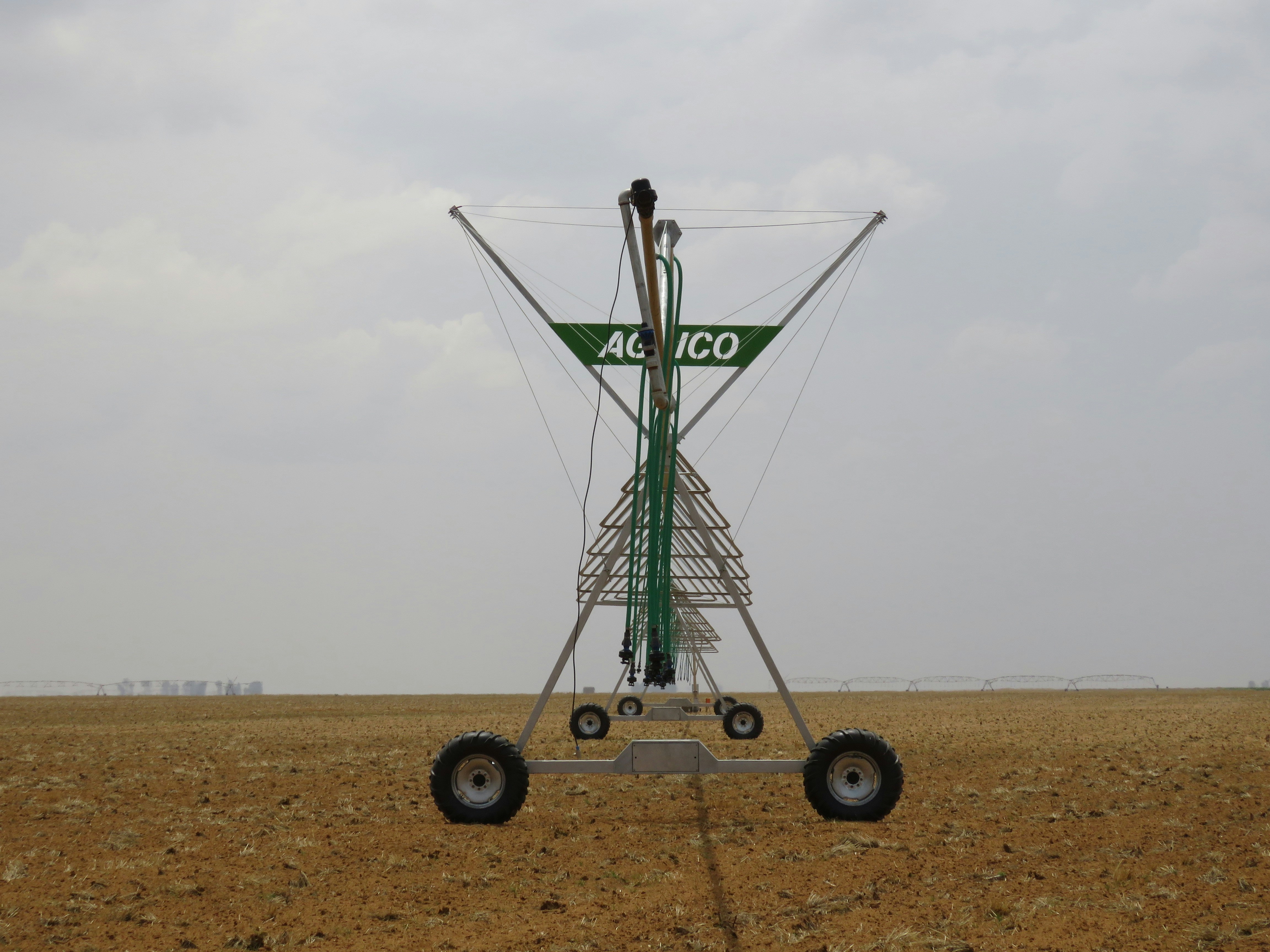 Center pivot irrigation system at dusk, dark atmospheric scene, deep shadows, moody industrial agricultural lighting