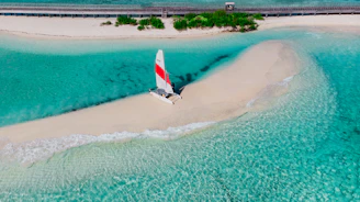 an aerial view of a sailboat on a beach