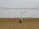 A large agricultural irrigation system is visible in a barren, flat field under an overcast sky. The system includes a long metallic structure with hoses hanging down from it, supported by a wheel.
