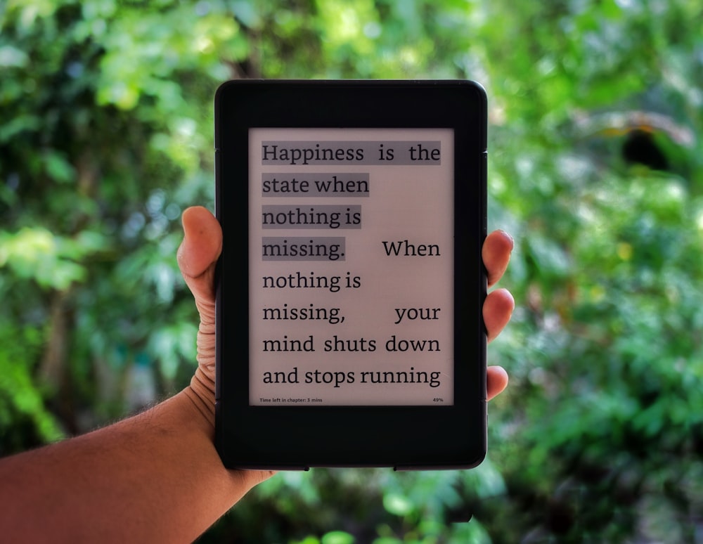 a person holding a kindle with a quote on it