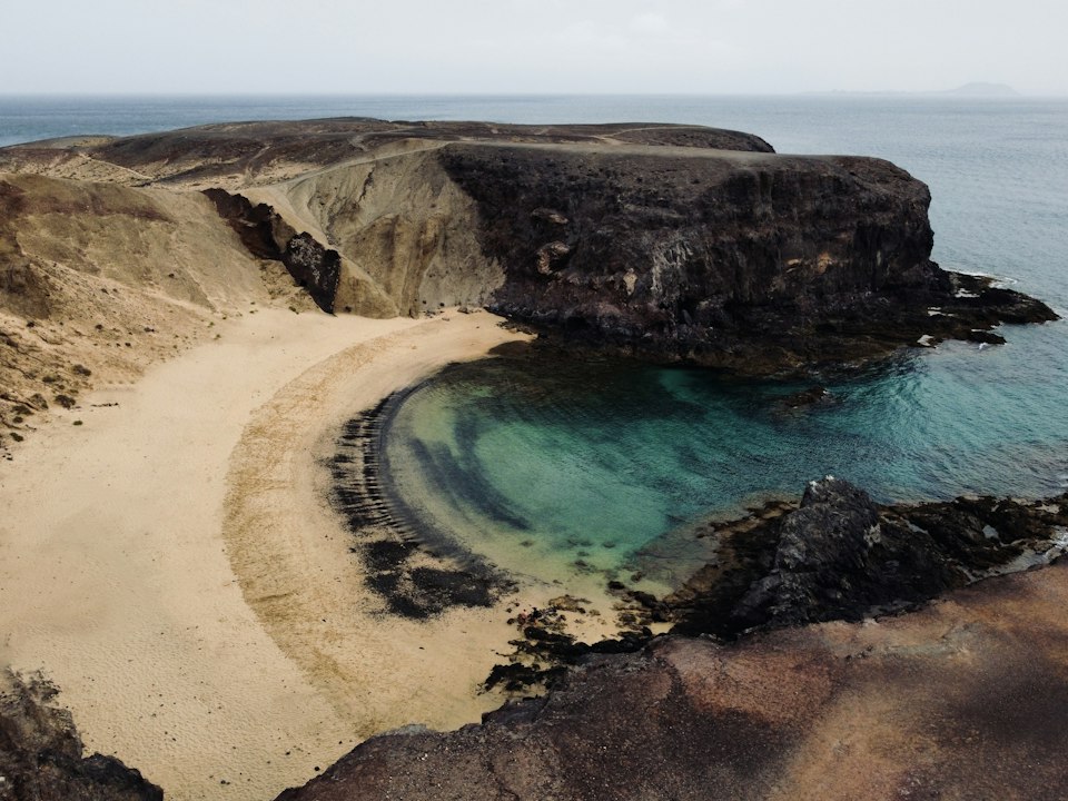 Turquoise cove of Playa del Papagayo framed by golden cliffs near Playa Blanca, Lanzarote