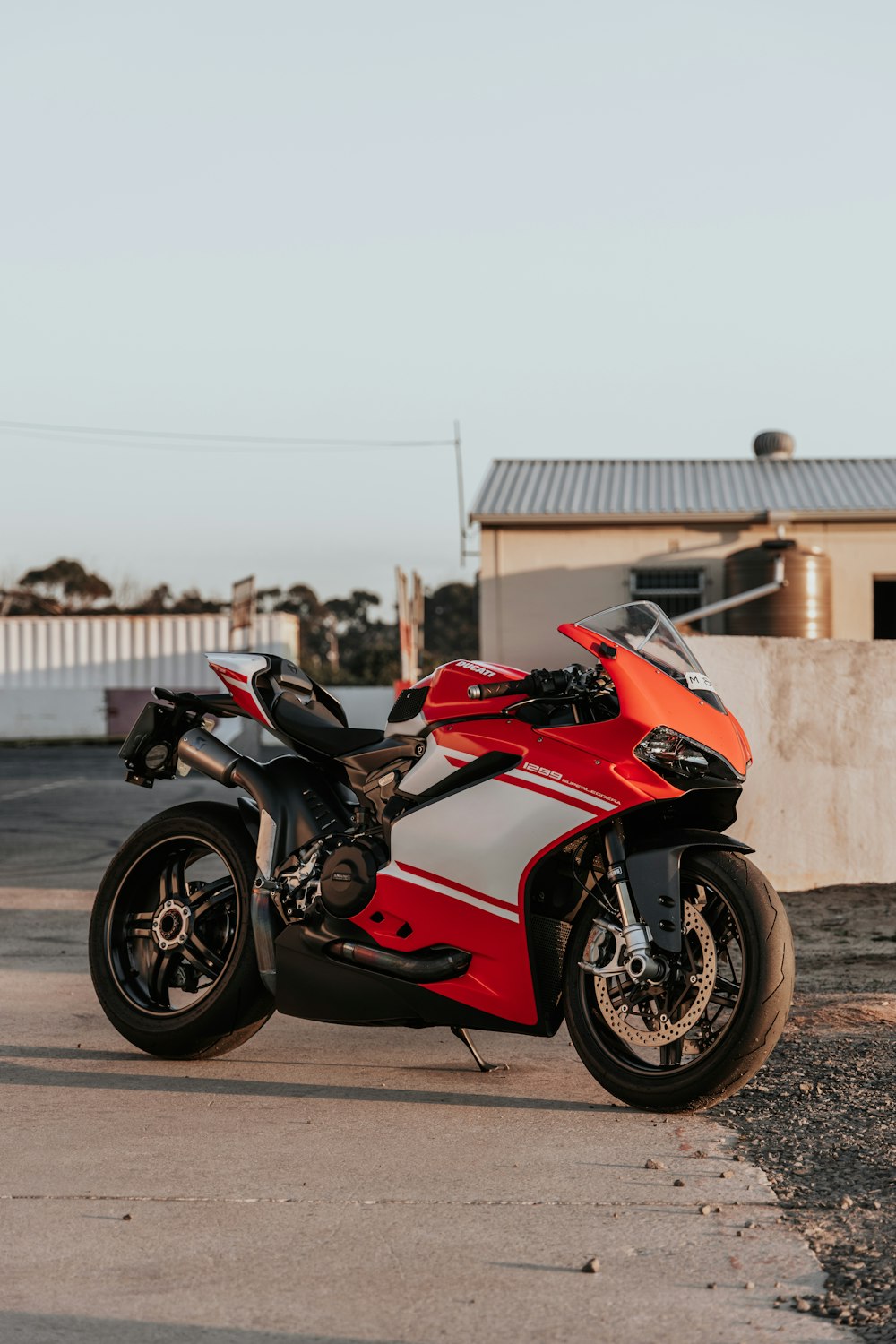 red and black sports bike parked on gray concrete pavement during daytime