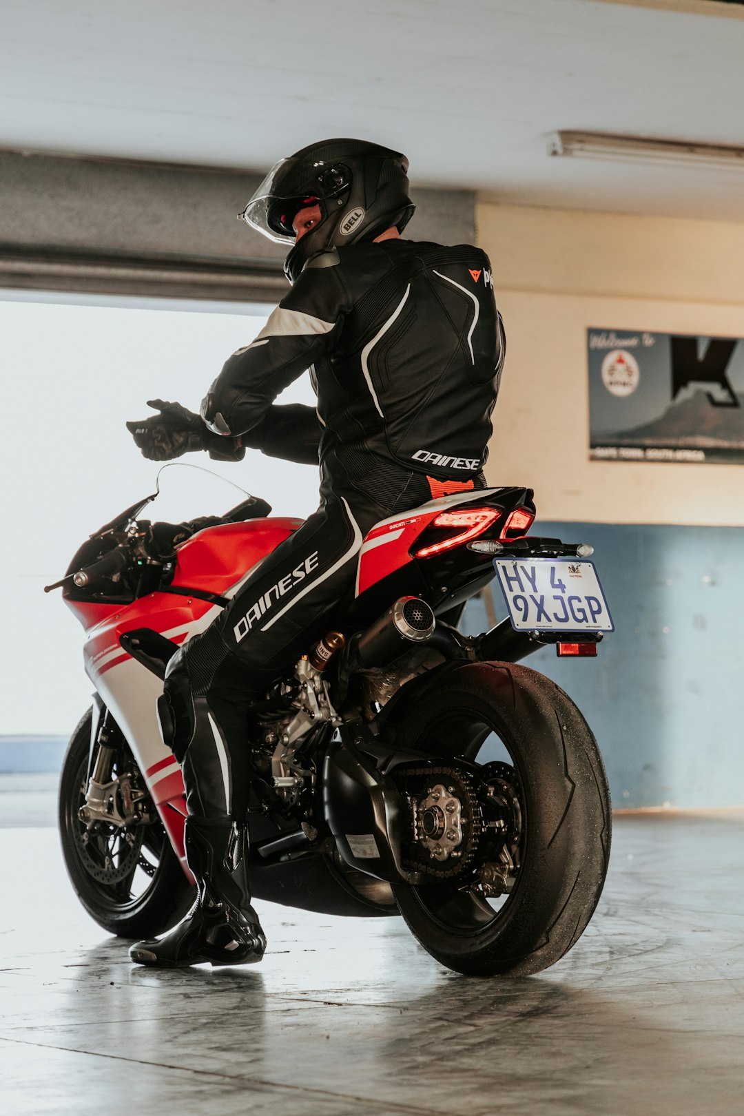 man in black and red motorcycle suit riding on red and black sports bike