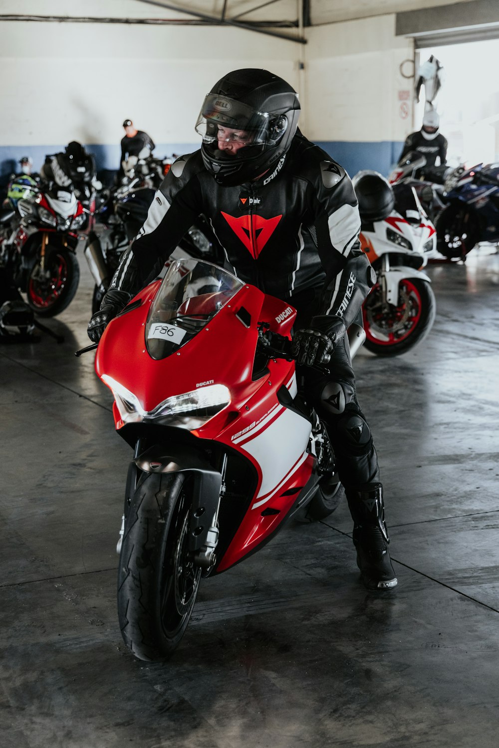 man in black and red motorcycle suit riding on red and white sports bike