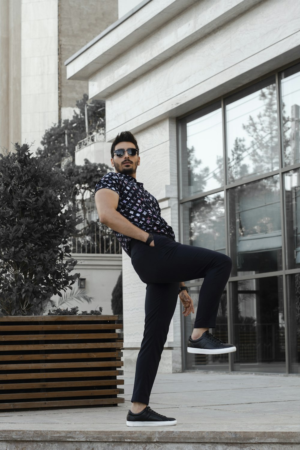 man in black and white checkered button up shirt and black pants standing on brown wooden