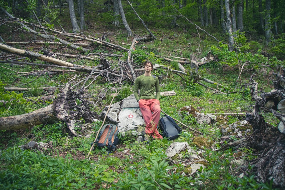 man in green long sleeve shirt sitting on tree log