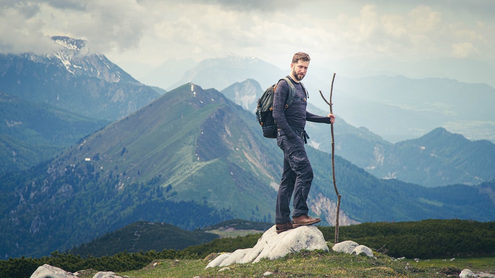 man in black jacket standing on rock