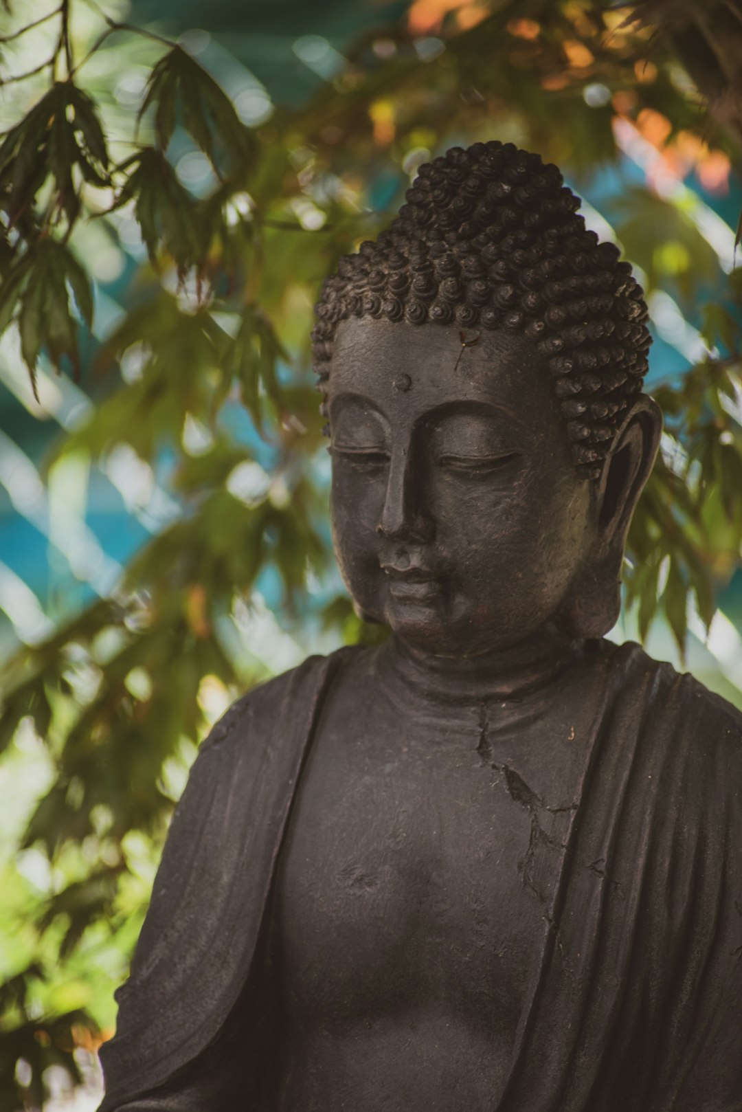 black buddha statue near green tree during daytime