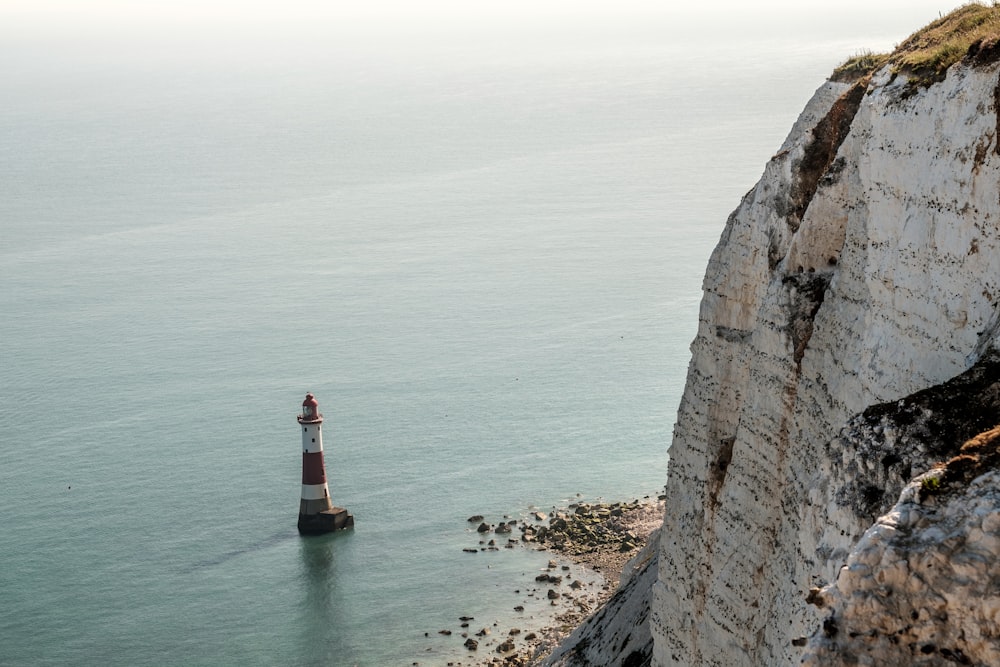 Phare rouge et blanc sur la montagne Rocheuse brune pendant la journée