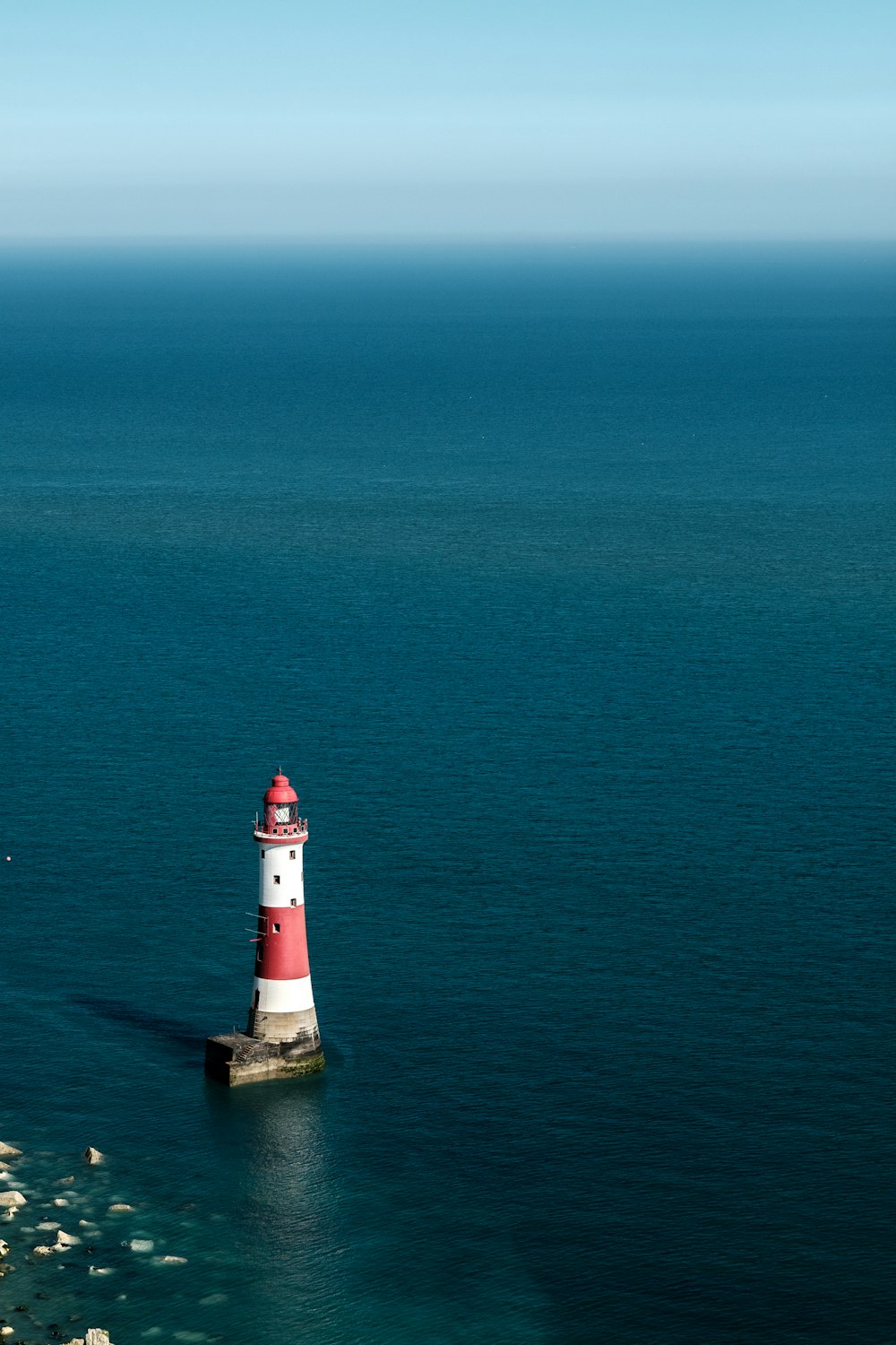 white and red lighthouse on the sea during daytime