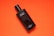 A black bottle of Davidoff Cool Water deodorant rests against a vibrant orange background. The bottle is sleek, with white text labeling it as mild deodorant. The contrast between the dark bottle and the bright background creates a striking visual.