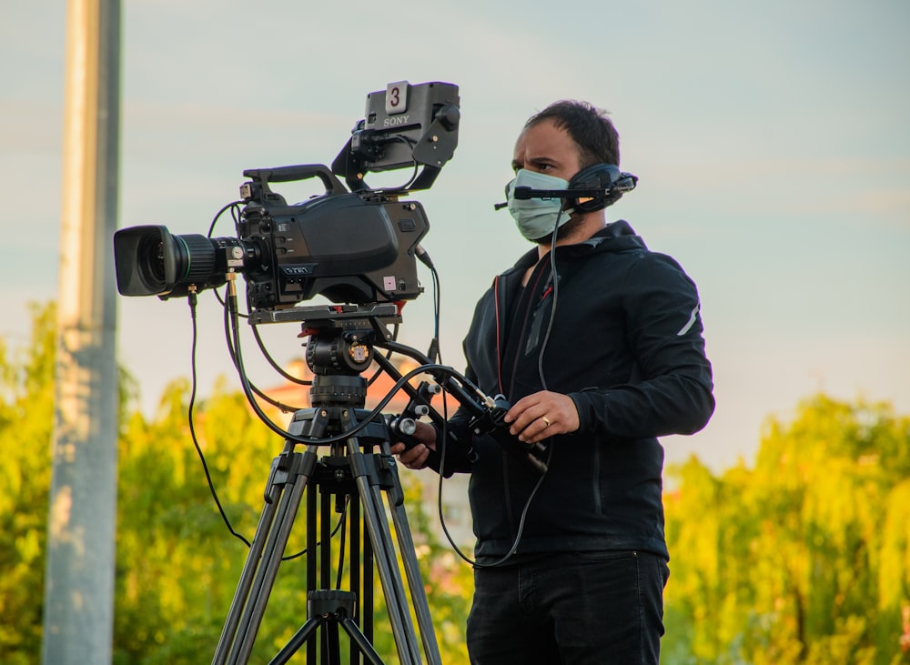 man in black jacket using black dslr camera