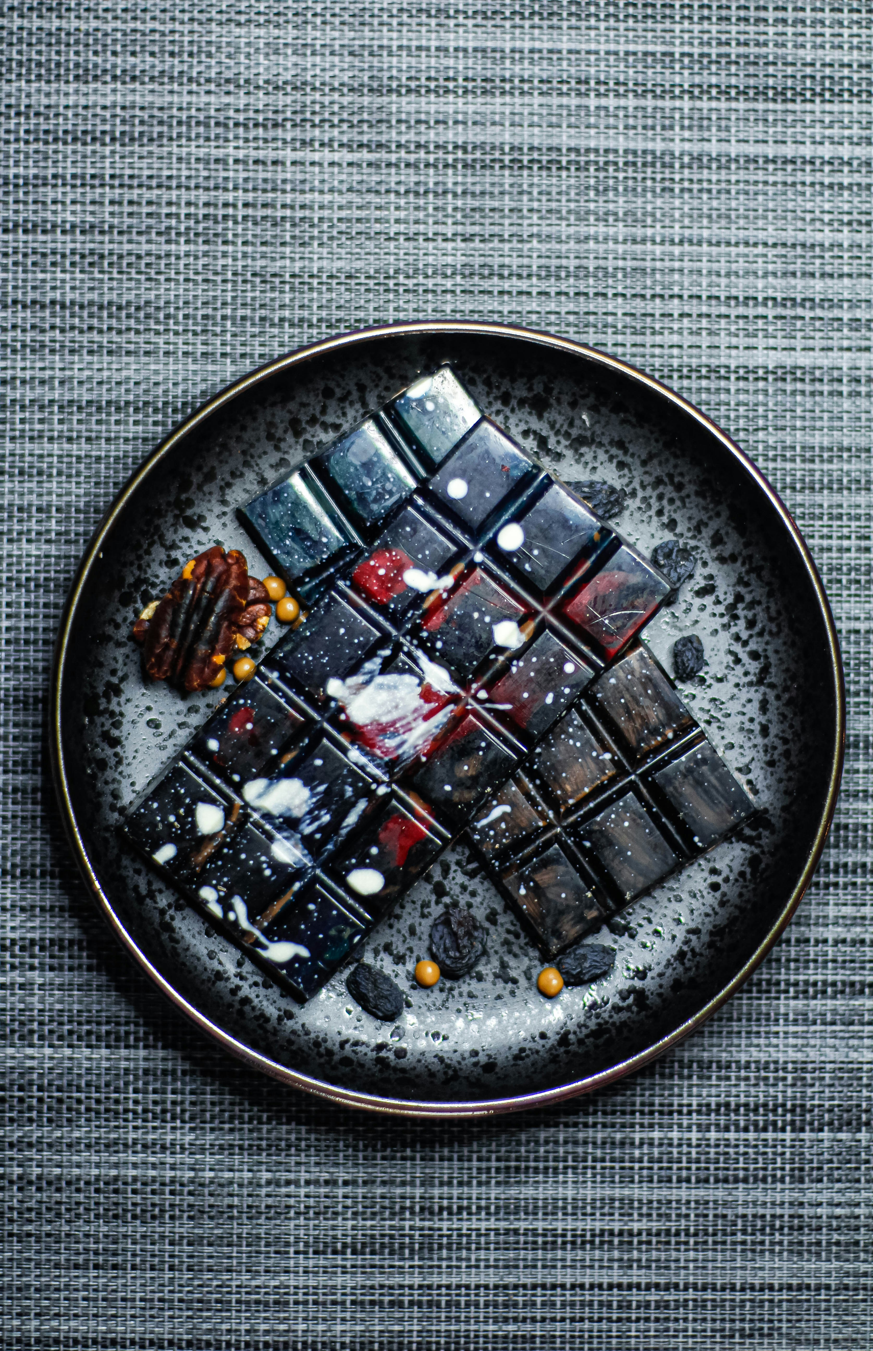 Dark chocolate bars arranged with nuts and candies on a plate.