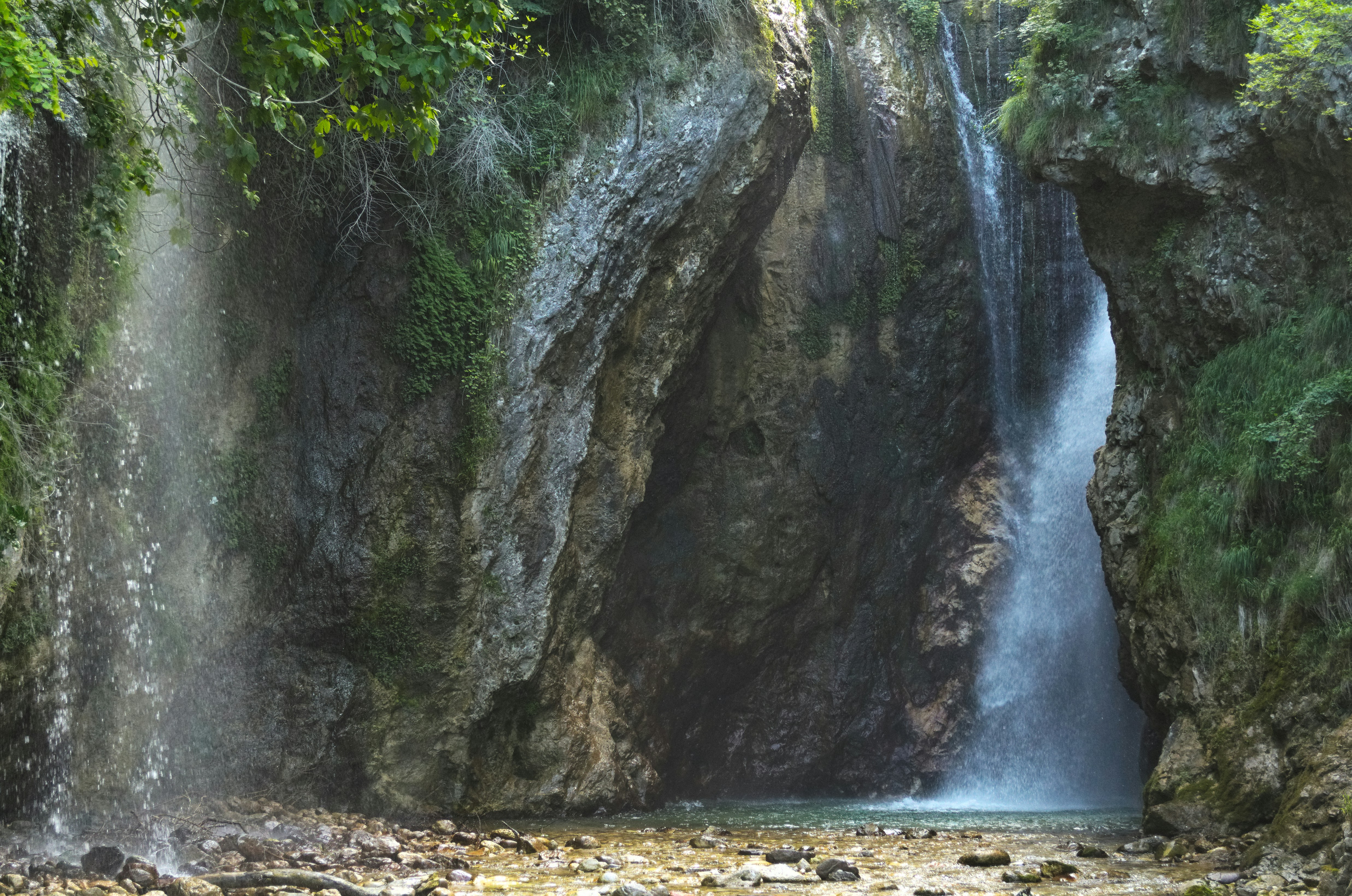 water falls on rocky shore during daytime