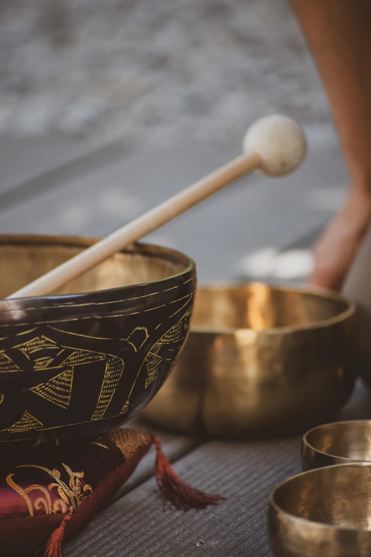 A wooden mallet resting beside a ceramic sound bowl on a quiet, neutral surface — the simplest tool kit for at-home sound cleansing