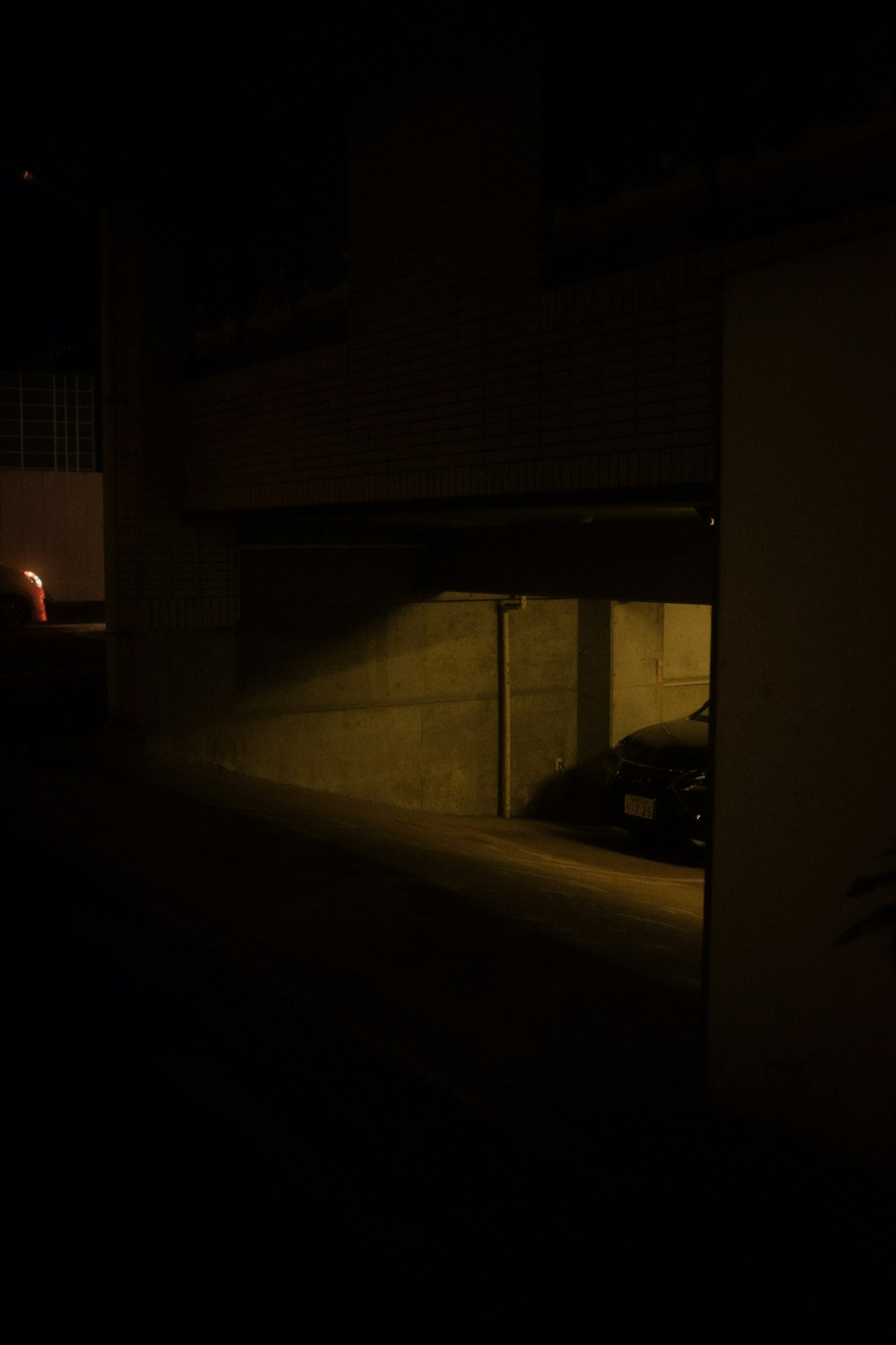 black car parked beside white concrete building during night time