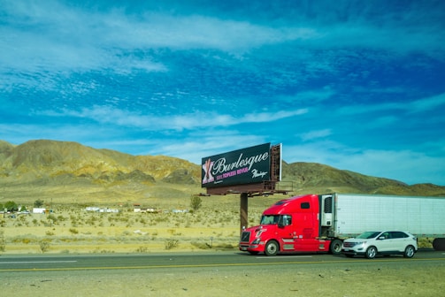 red and white truck on brown field under blue sky during daytime
