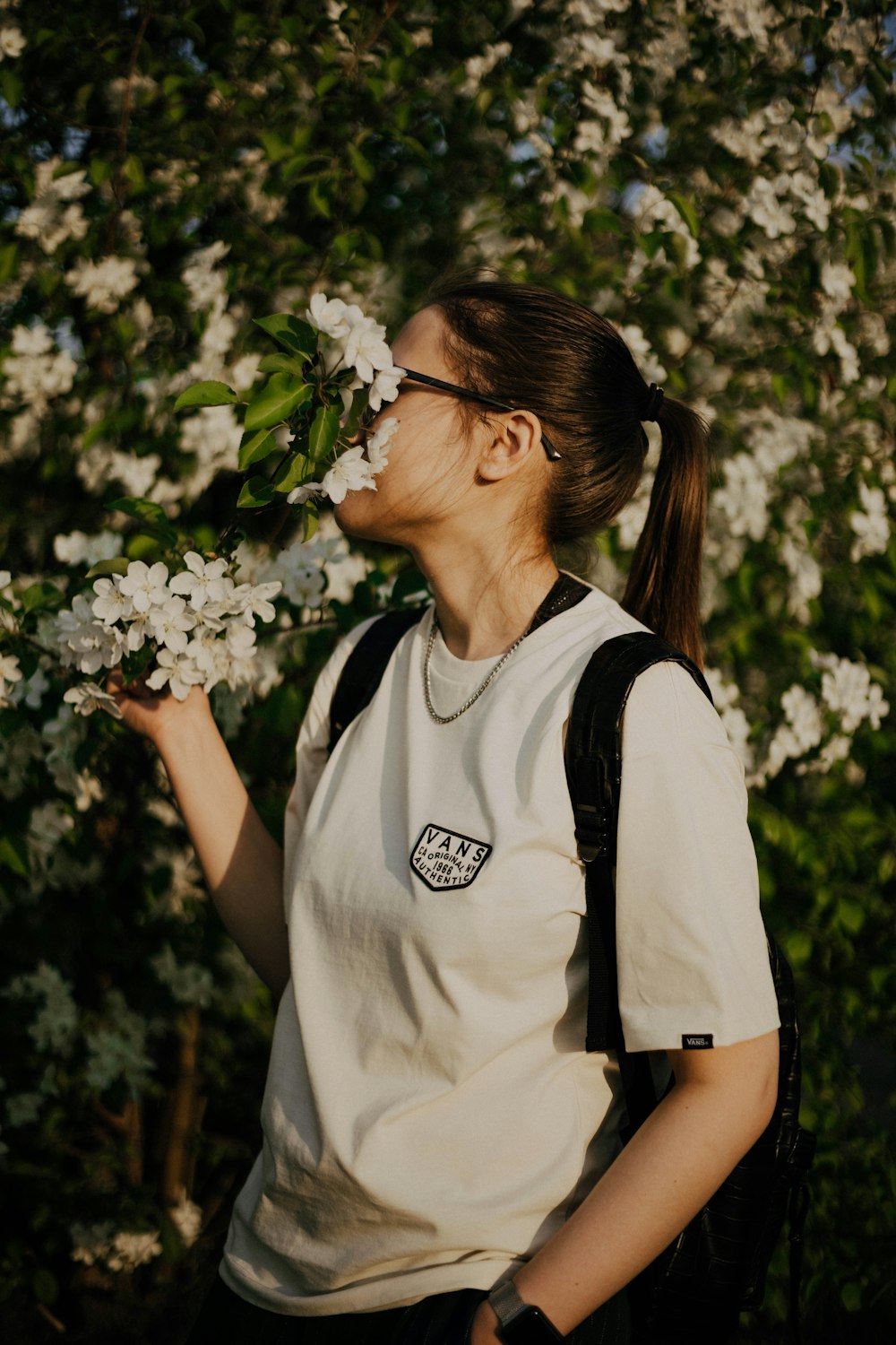 woman in white and black crew neck t-shirt holding white flowers