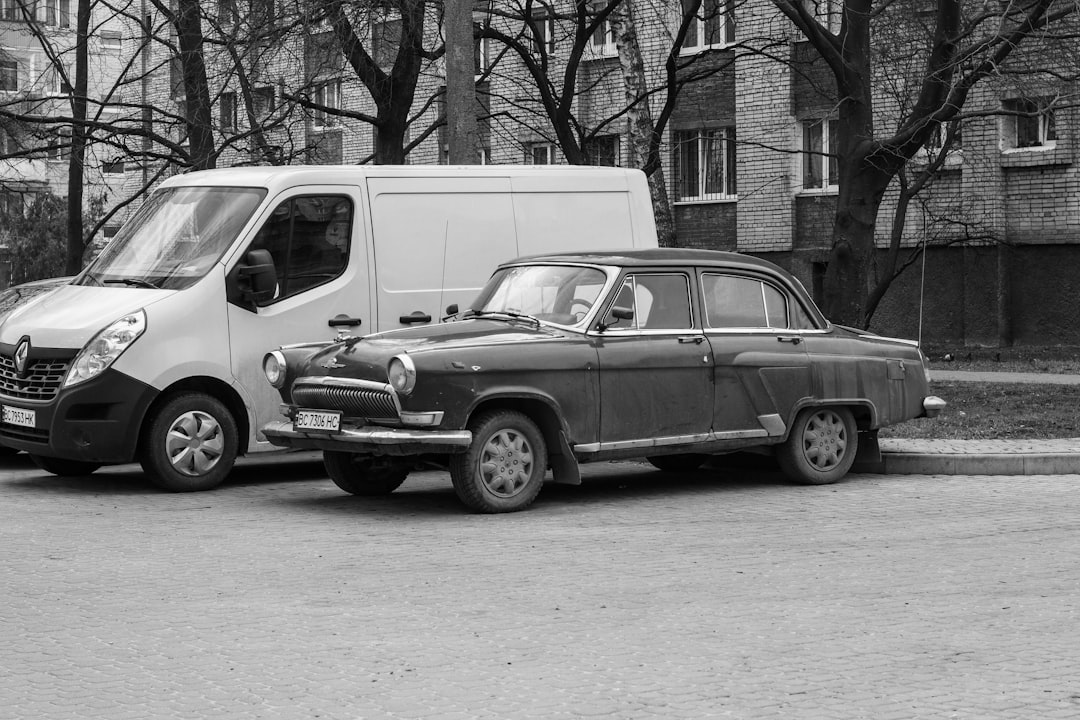 grayscale photo of suv parked beside building