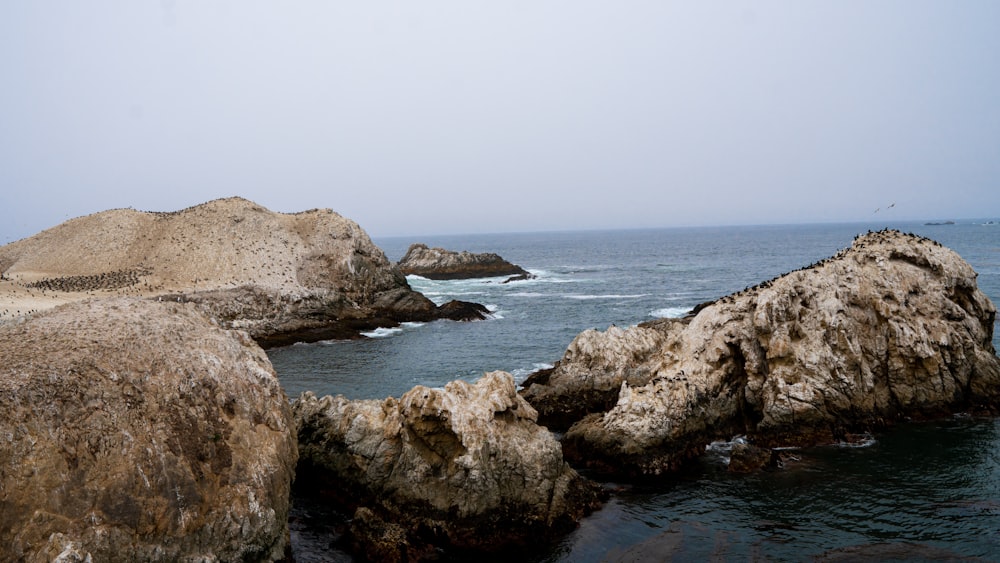 brown rocky mountain beside body of water during daytime