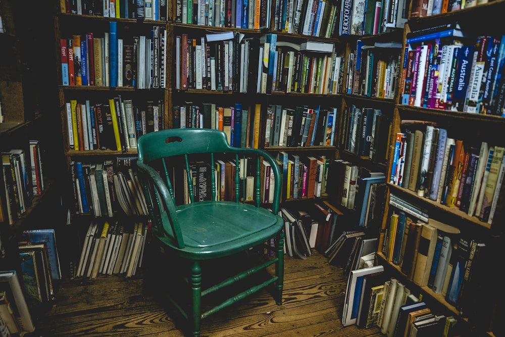 茶色の木製の本棚の近くの緑色のプラスチックの椅子