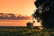 white and brown wooden house near green grass field during sunset