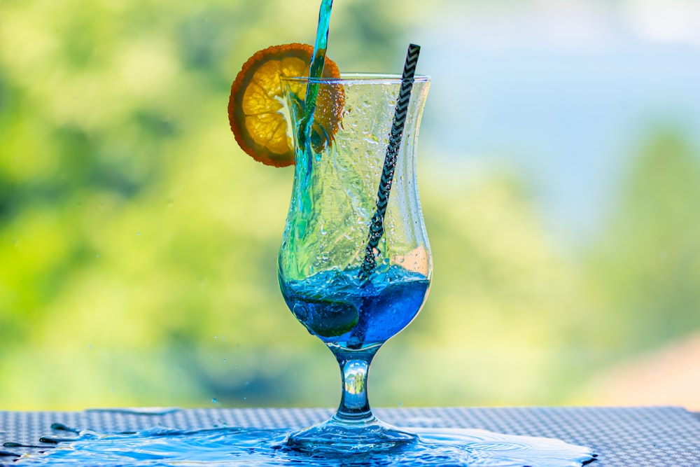 blue liquid in clear wine glass with sliced orange fruit