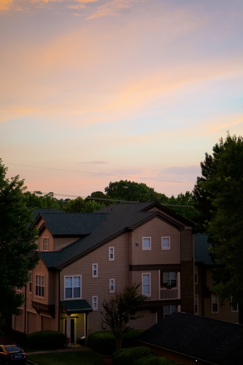 brown and white house near green trees under white sky during daytime