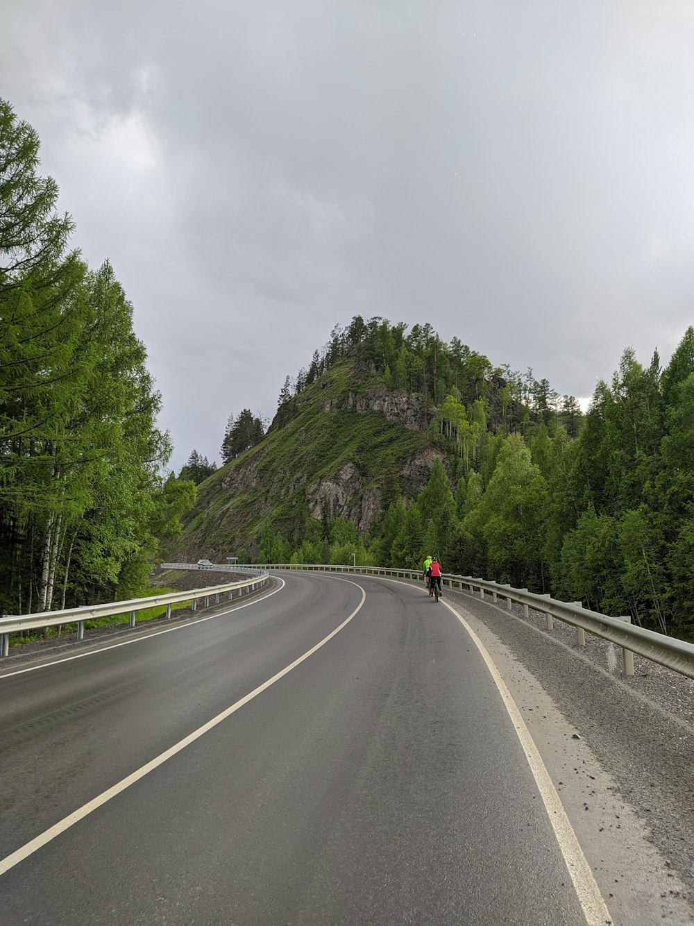 person in red jacket and black pants walking on gray concrete road during daytime