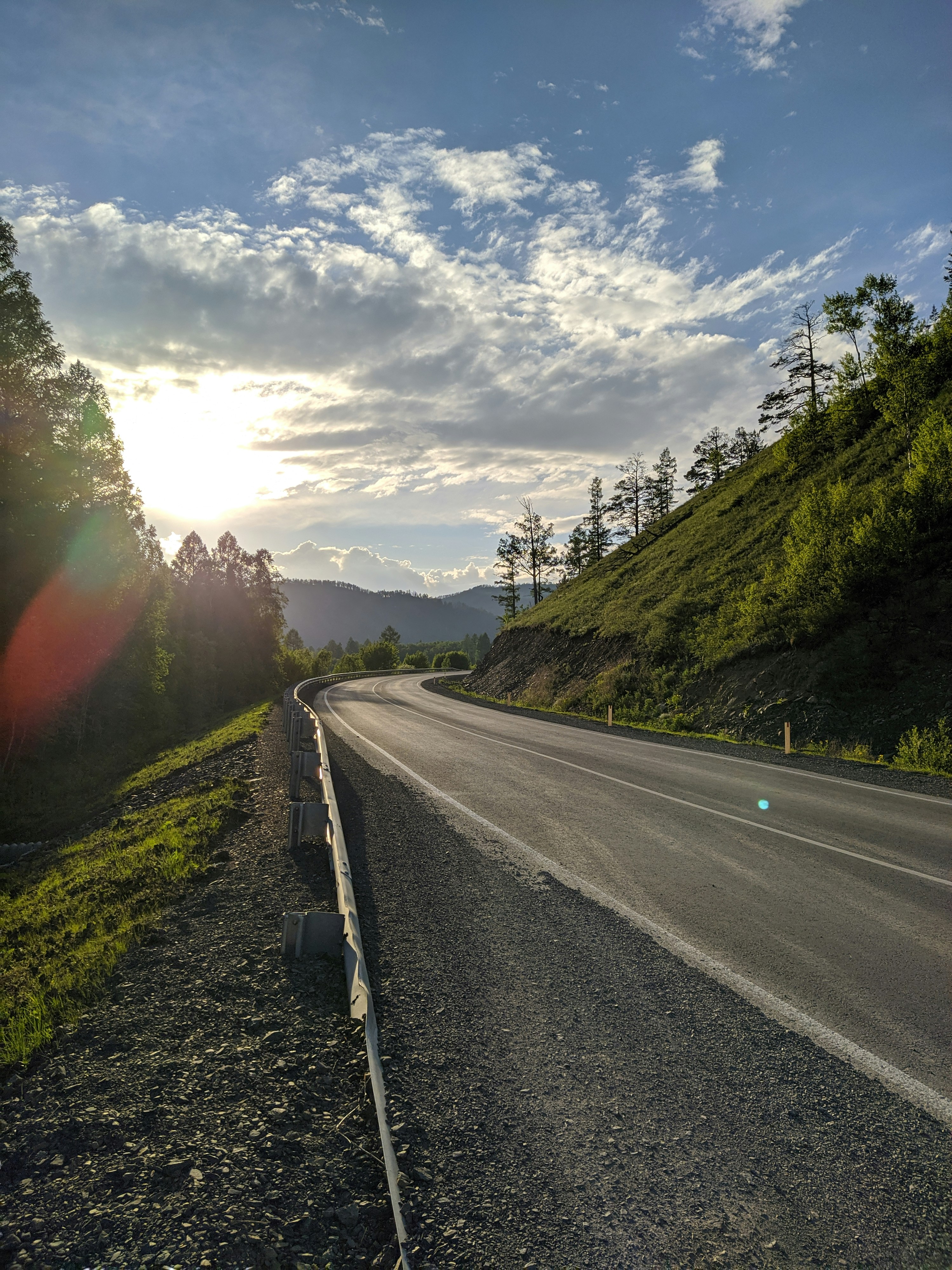 gray concrete road between green grass field during daytime