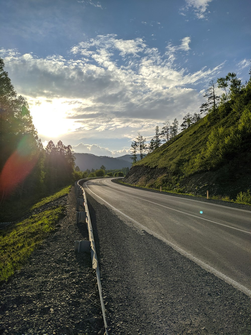 昼間の緑の芝生の間の灰色のコンクリート道路