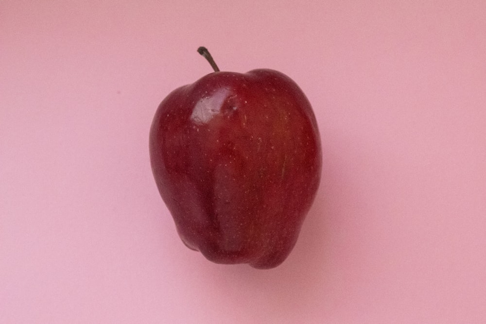 red apple on pink surface