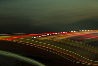 Streaks of colorful light trails move across a dark background, producing an abstract and dynamic visual effect. The trails include red, yellow, orange, and white colors.