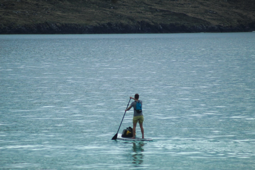 mulher no biquíni amarelo e preto que monta no caiaque amarelo no mar azul durante o dia