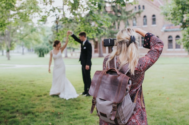 woman in red and black floral dress carrying black leather shoulder bag