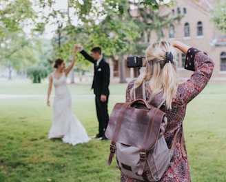 woman in red and black floral dress carrying black leather shoulder bag