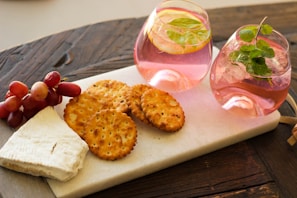 A stylish snack presentation featuring a glass of wine and a small plate of savory treats on a marble table.
