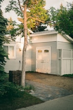white wooden house near green tree during daytime