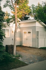 white wooden house near green tree during daytime
