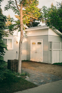 white wooden house near green tree during daytime