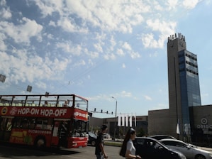 A vibrant city tour bus passing famous landmarks under a clear blue sky.