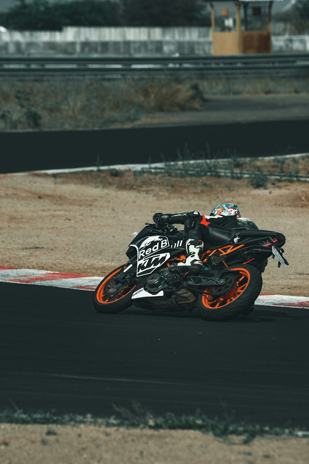 uomo in casco da moto in bianco e nero che guida su una moto sportiva nera e arancione