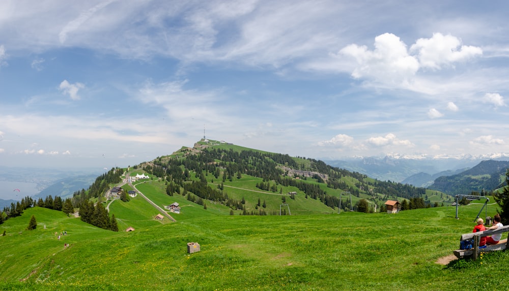 green grass field near green mountains under blue sky during daytime