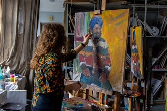 woman in black and brown floral long sleeve shirt holding painting of man in blue denim