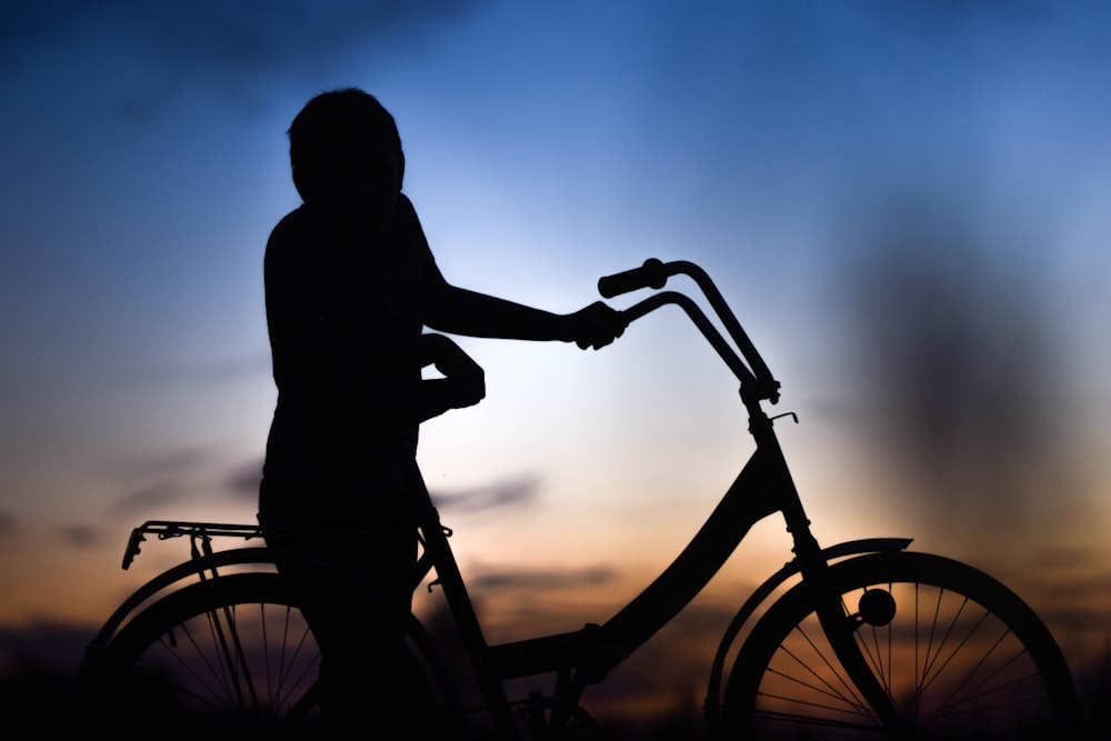 a silhouette of a person standing next to a bike