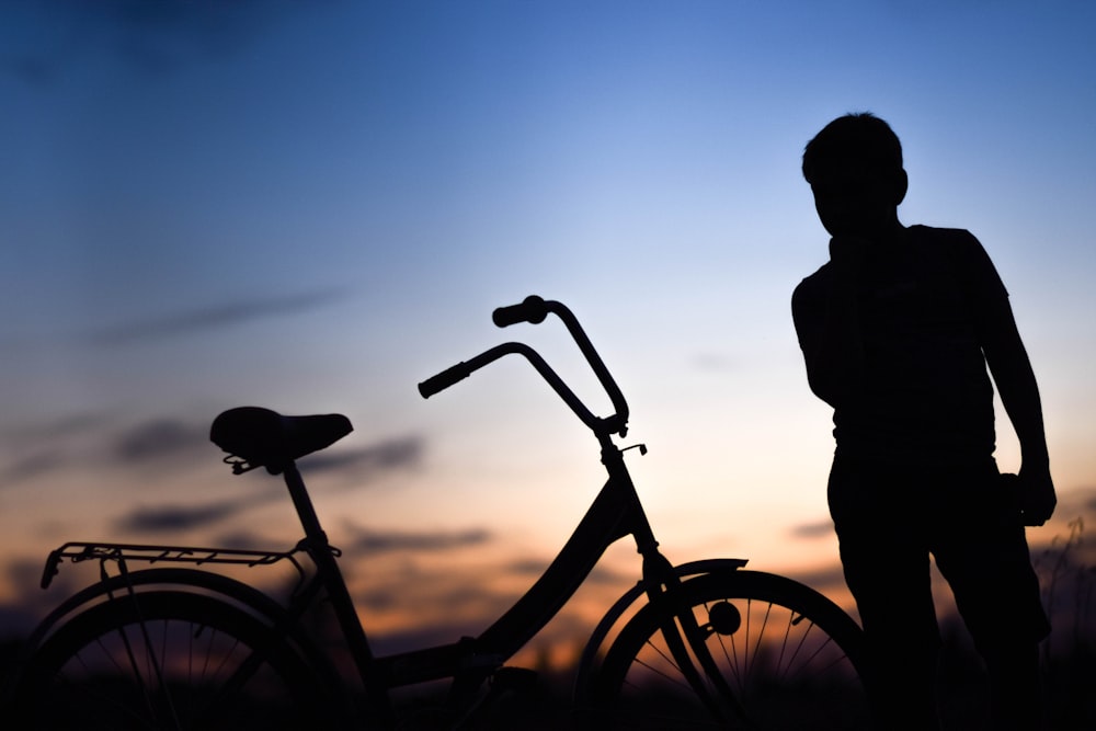 a silhouette of a person standing next to a bike
