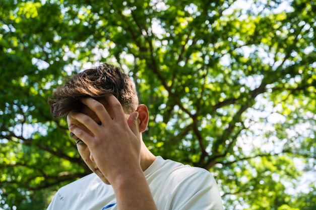 man in white crew neck t-shirt covering his face with his hand