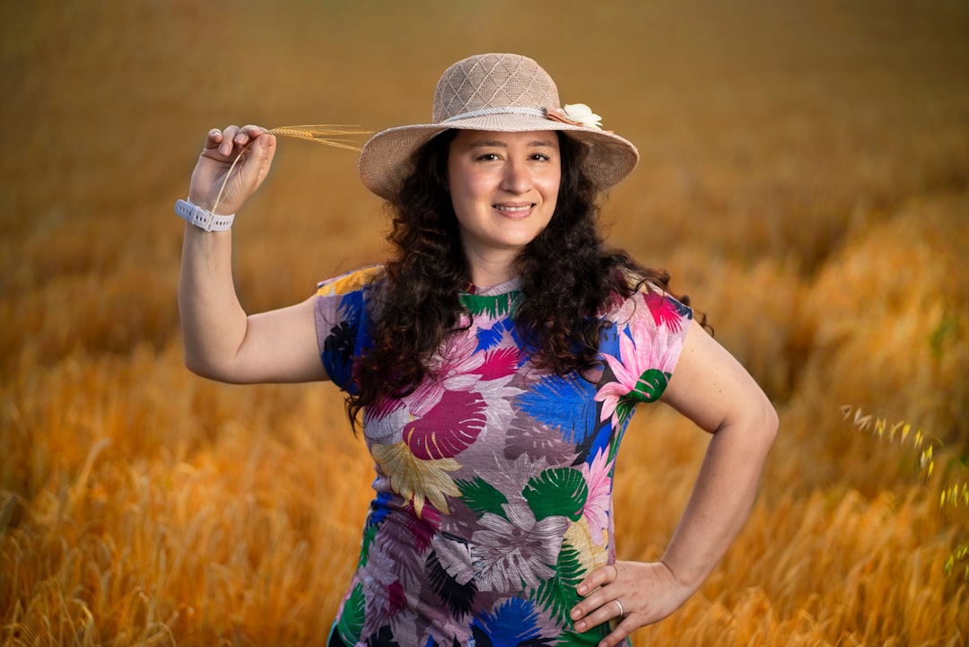 woman in blue yellow and red floral sleeveless dress wearing white sun hat