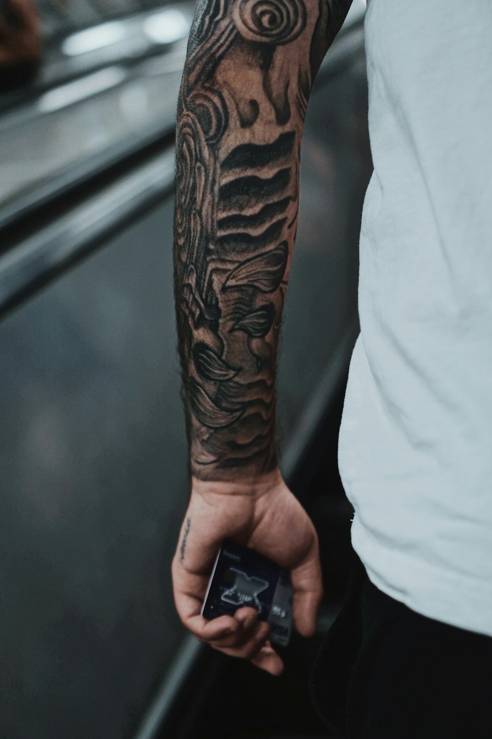 Person mit schwarzem Tattoo mit schwarzem Smartphone